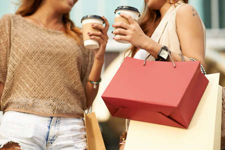 Cropped image of female shopaholics chatting and drinking coffeeの写真素材