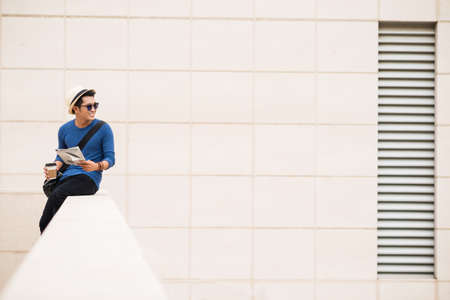 Smiling man with newspaper sitting on the balcony of office buildingの写真素材