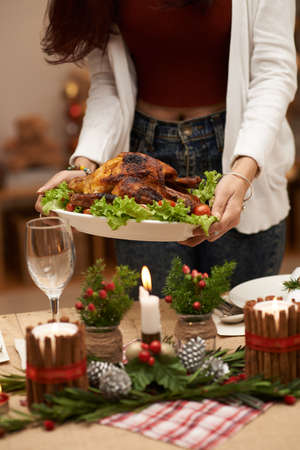 Woman putting main dish on the Christmas tableの写真素材