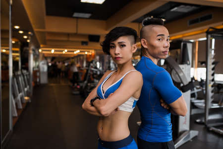 Asian young sporty man and woman standing in the gym back to backの写真素材