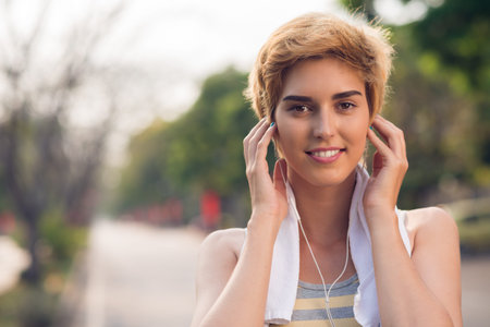 Face of cheerful girl listening to music when working out outdoorsの写真素材
