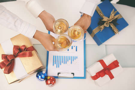 Hands of managers clinking glasses above financial chartの写真素材