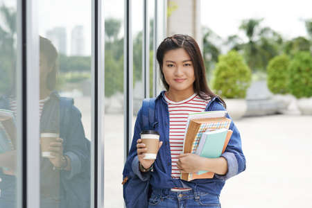 College girl with take-out coffee and textbooks going to classesの写真素材