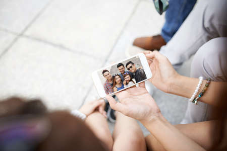 Group of teenagers watching themselves on smartphoneの写真素材
