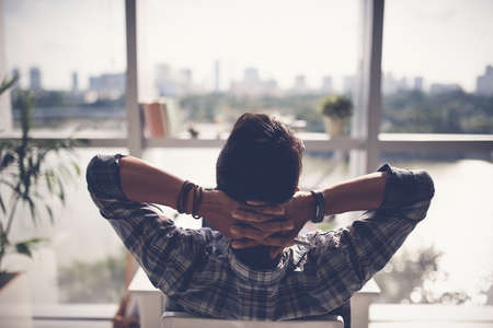 Man relaxing in his chair and enjoying the view from office windowの写真素材