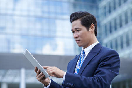 Portrait of businessman checking email on his touchpadの写真素材