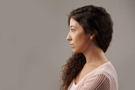 Profile of beautiful curly brunette looking in front of herの写真素材