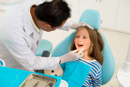 Dentist examining teeth and gums of little girlの写真素材