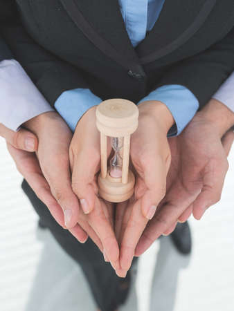 Little hourglass in hands of business teamの写真素材