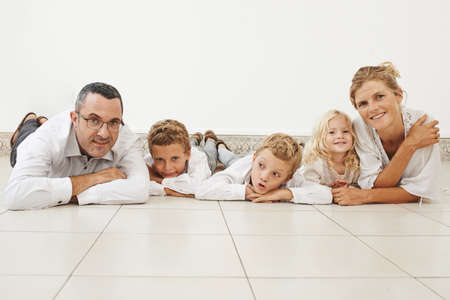 Happy large family lying on the floor and looking at the cameraの写真素材