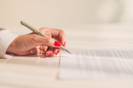 Close-up of female hand ready to sign a documentの写真素材
