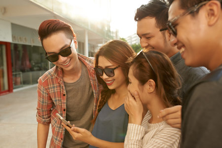 Group of teenage friends enjoying photos on smartphone