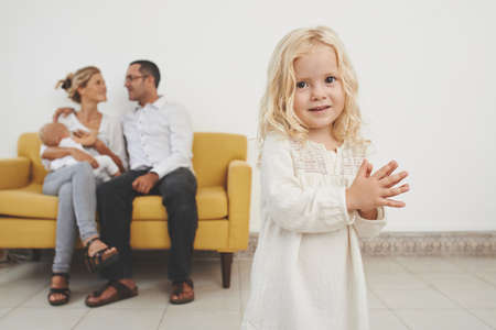 Portrait of adorable little girl, her parents and younger sister in the backgroundの写真素材