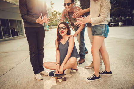 Teenage friends giving a ride to their girlfriend on skateboardの写真素材