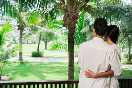 Couple enjoying the view from hotel balcony, view from the backの写真素材