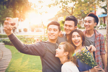 Cheerful teenage friends taking selfie against sunsetの写真素材