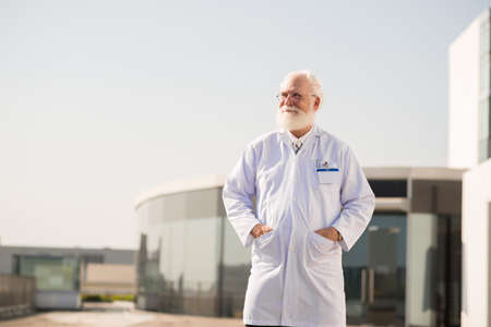 Senior man standing in lab coat at his research centerの写真素材