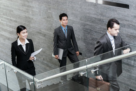 Asian business people walking up the stairs in the officeの写真素材