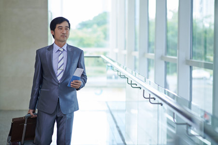 Vietnamese businessman with passport and ticket going to airport gateの写真素材