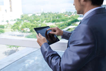 Business person using tablet computer when standing at windowの写真素材