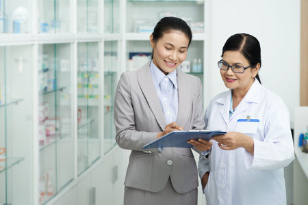Asian business woman showing document to pharmacy workerの写真素材