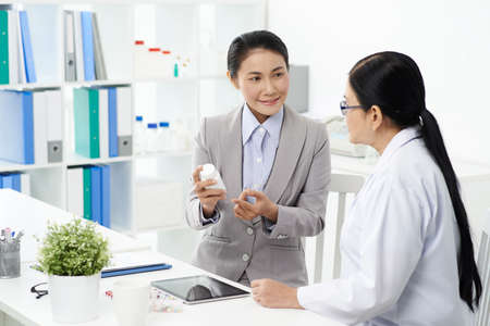 Vietnamese business lady consulting on medicine with pharmacistの写真素材