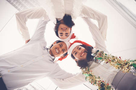 Vietnamese business team in Santa hats looking down and smiling at cameraの写真素材