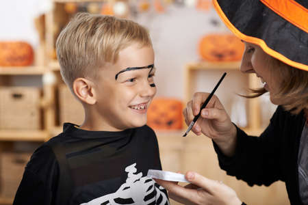 Mother painting face of her son for Halloween celebrationの写真素材