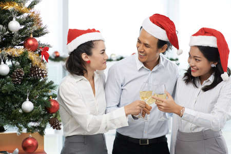 Business colleagues laughing when clinking glasses at the Christmas partyの写真素材