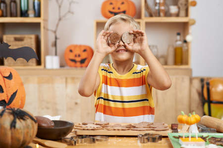 Funny boy covering his eyes with homemade Halloween cookiesの写真素材