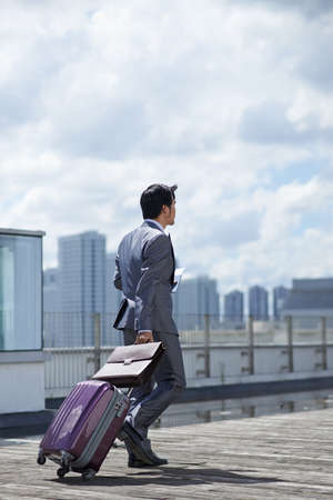Businessman with suitcase and ticket going to airport terminalの写真素材