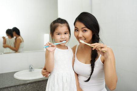 Vietnamese mother and daughter brushing teeth togetherの写真素材