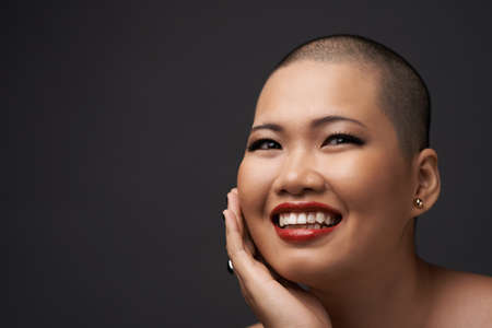 Portrait of woman with perfect skin smiling and touching her faceの写真素材