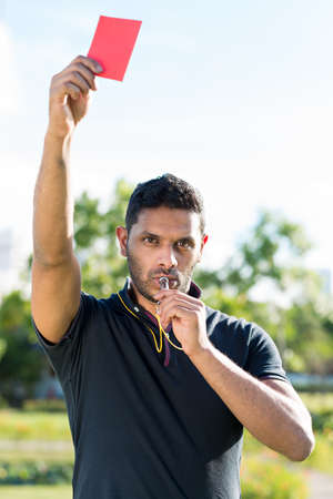 Referee whistling and showing red card as a symbol of penaltyの写真素材