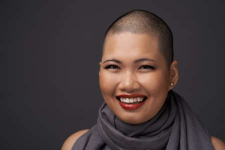 Face of laughing Vietnamese woman with shaved hairstyleの写真素材