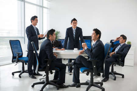 Composite image of entrepreneur having business meeting with his clonesの写真素材