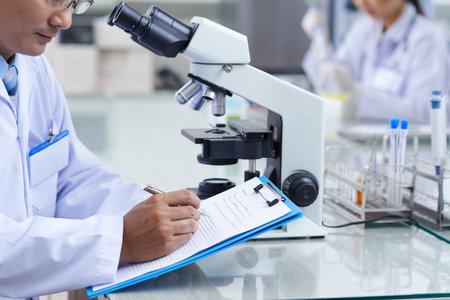 Cropped image of doctor filling document after conducting research
