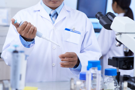 Cropped image of chemist using dropper to fill test-tube with reagent