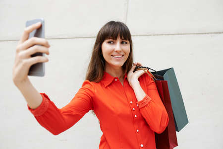Pretty woman with paper-bags talking selfieの写真素材
