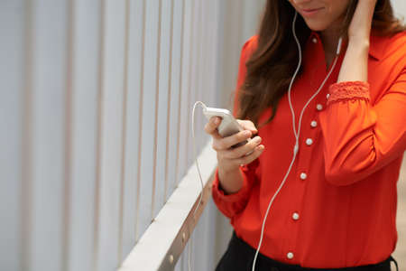 Cropped image of woman listening to the music and using application on her phoneの写真素材