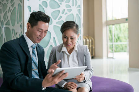Smiling coworkers discussing information on the digital tabletの写真素材