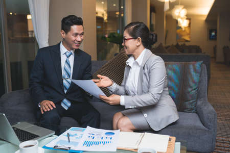 Asian businessman and businesswoman discussing documents in pleasant cafeの写真素材