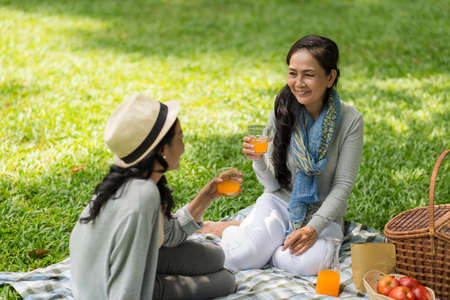 Vietnamese senior women drinking juice and gossiping in the parkの写真素材
