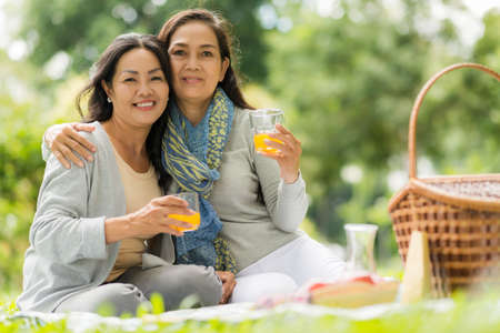 Portrait of Vietnamese female friends hugging and looking at the cameraの写真素材