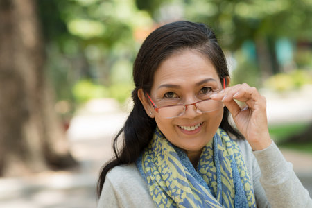 Portrait of Vietnamese senior woman in glasses looking at the cameraの写真素材