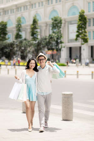 Full-length portrait of cheerful Vietnamese couple with many shopping bagsの写真素材