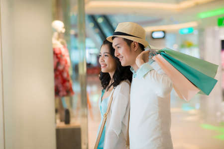 Smiling couple looking at the showcase in the shopping mallの写真素材