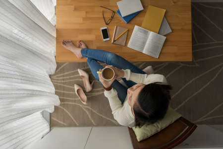 Girl having break with a cup of coffee after doing homeworkの写真素材