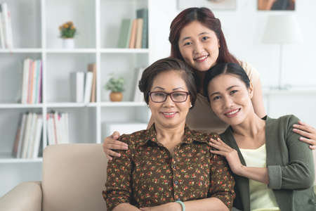 Asian teenage girl embracing her mother and grandmotherの写真素材