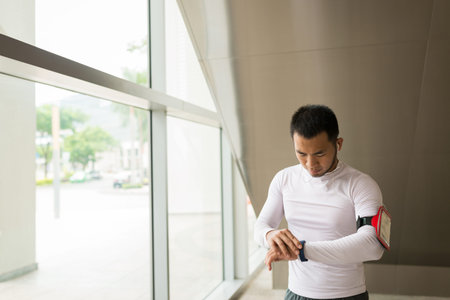 Vietnamese sportsman checking pedometer after joggingの写真素材